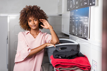 Young black African American woman washing her clothes in a automatic laundry