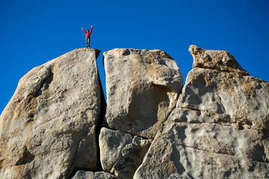 Mitch Underhill holding his arms up on top of a rock while climbing in Owens River Gorge near Bishop, California.