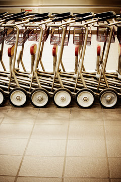 A row of empty luggage carts in airport.