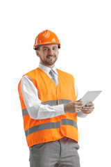 The builder in a construction vest and an orange helmet with tablet. Safety specialist, engineer, industry, architecture, manager, occupation, businessman, job concept