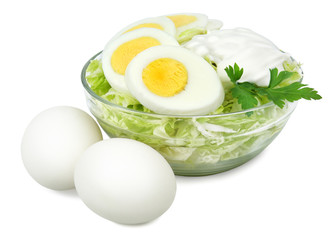 Glass bowl with a salad of cabbage boiled eggs and sour cream isolated on white background.