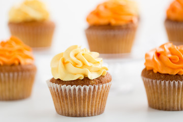 food, pastry and sweets concept - close up of cupcakes with buttercream frosting over white...
