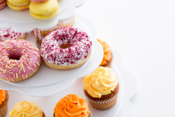 fast food, dessert and sweets concept - close up of glazed donuts and cupcakes on stand
