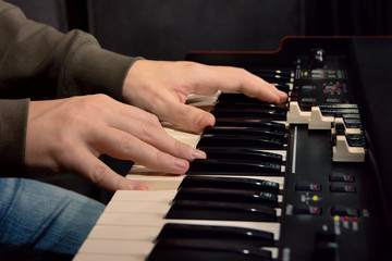 close-up of hand person playing a piano keyboard in spotlights