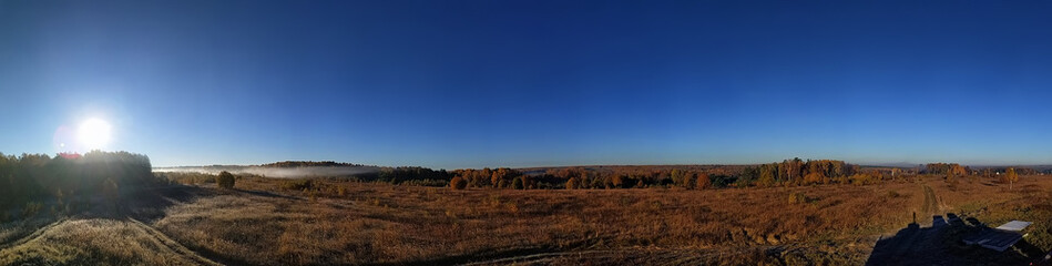 Fototapeta premium Amazing panorama of the rural autumn landscape of a European village with a colorful sky and an infinite golden field.