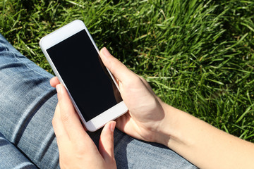 Woman holding and using smartphone outdoor