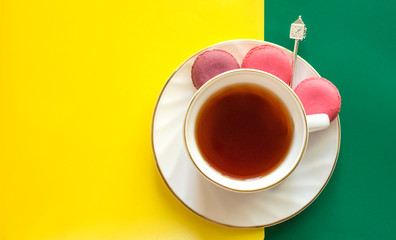 Cup of tea with colorful almond cookies on an abstract yellow-green background.copy space