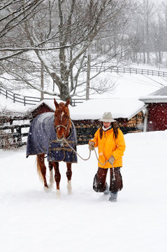 Woman Standing With Her Horse In Snowy Landscape