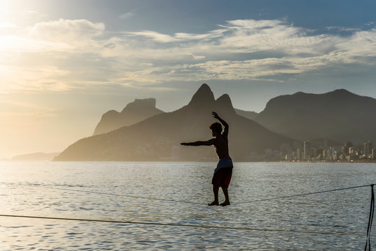 A Man Balances On A Slackline At Arpoador Beach During The Sunset, Rio De Janeiro, Brazil