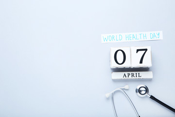 Text World Health Day with stethoscope and cube calendar on grey background