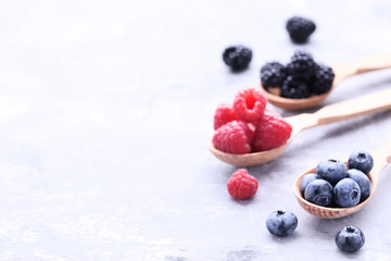 Ripe and sweet fruits in spoons on grey wooden table