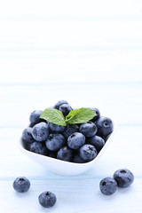 Ripe blueberries with green leafs on wooden table