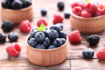 Ripe and sweet fruits in bowls on brown wooden table