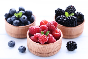Ripe and sweet fruits in bowls on white wooden table