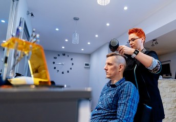 Hairdresser drying male customer hair in salon