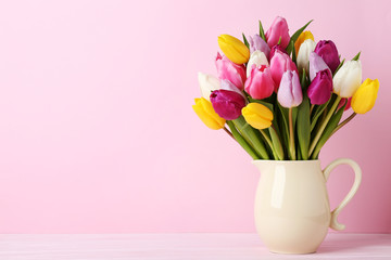 Bouquet of tulips in jug on wooden table