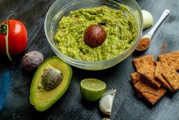 green, naturally made traditional guacamole surrounded by fresh ingredients and nachos