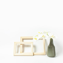 White Phalaenopsis orchid flowers in gray vase and wooden photo frames on white background. Tropical flower, branch of orchid. Holiday, Women's Day, Flower Card flat lay. Interior details Mockup