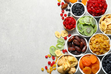 Bowls of different dried fruits on grey background, top view with space for text. Healthy food