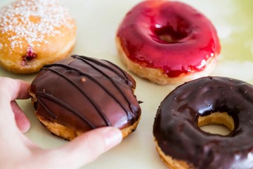 assorted donuts with chocolate frosted, pink glazed and sprinkles donuts.