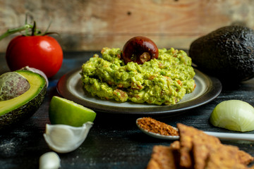 green, naturally made traditional guacamole surrounded by fresh ingredients and nachos