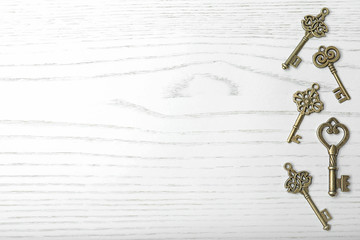 Old vintage keys on wooden background, flat lay. Space for text