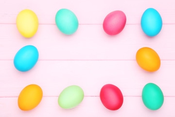 Colorful easter eggs on pink wooden table