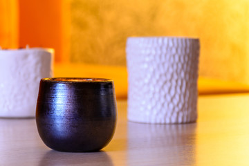 Handmade candle in dark candlestick on wooden table. Front view. Healthy lifestyle concept