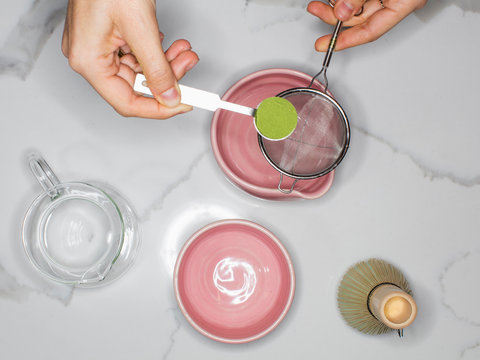 Person preparing green tea matcha with powder on measuring spoon