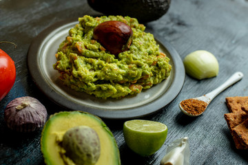 green, naturally made traditional guacamole surrounded by fresh ingredients and nachos