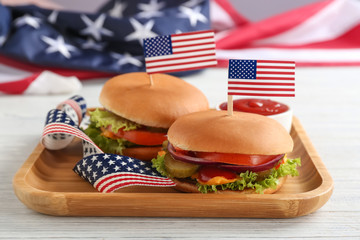Tasty burgers with USA flags and sauce on table. Traditional American food