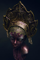 Head of mannequin in decorated bronze kokoshnick, dark studio background