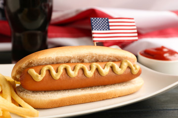 Tasty hot dog with USA flag on table, closeup. Traditional American food