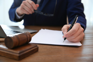 Notary working with papers and judge gavel on table, closeup. Law and justice concept