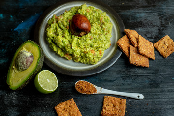 green, naturally made traditional guacamole surrounded by fresh ingredients and nachos