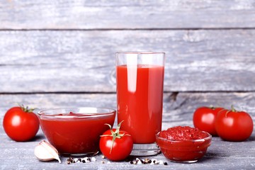 Tomato juice in glass with ketchup and garlic on wooden table