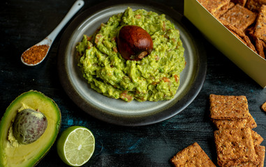 green, naturally made traditional guacamole surrounded by fresh ingredients and nachos