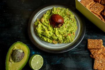 green, naturally made traditional guacamole surrounded by fresh ingredients and nachos