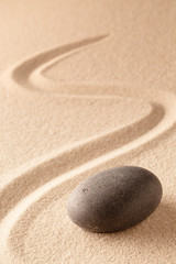 black round zen meditation stone for focus and concentration in Japanese sand garden. Textured background with copy space for mindfulness or spa wellness.