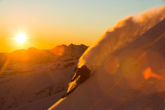 Man skiing through fresh snow at sunset in mountains