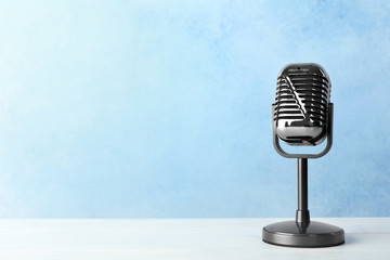 Retro microphone on table against color background. Space for text