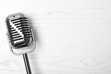 Retro microphone on wooden background, top view with space for text