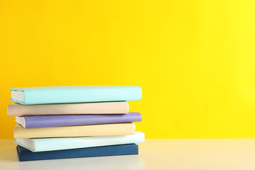 Stack of books on table against color background. Space for text