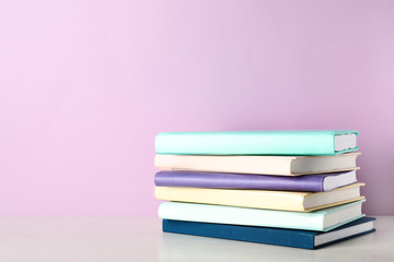 Stack of books on shelf against color background. Space for text