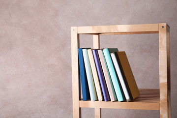 Different books on shelf against color background. Space for text