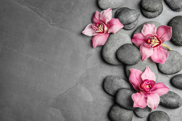 Zen stones and exotic flowers on dark background, top view with space for text