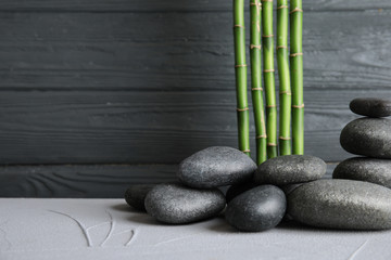 Obraz na płótnie Canvas Zen stones and bamboo on table against wooden background. Space for text