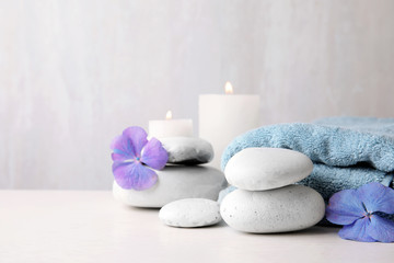 Composition with zen stones, towel and candles on table against light background. Space for text