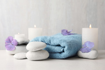 Composition with zen stones, towel and candles on table against light background