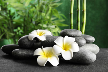 Zen stones and exotic flowers on table against blurred background